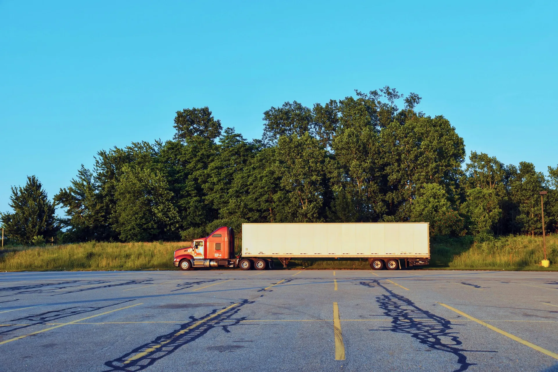 Red semi truck and trailer staged in a transportation yard