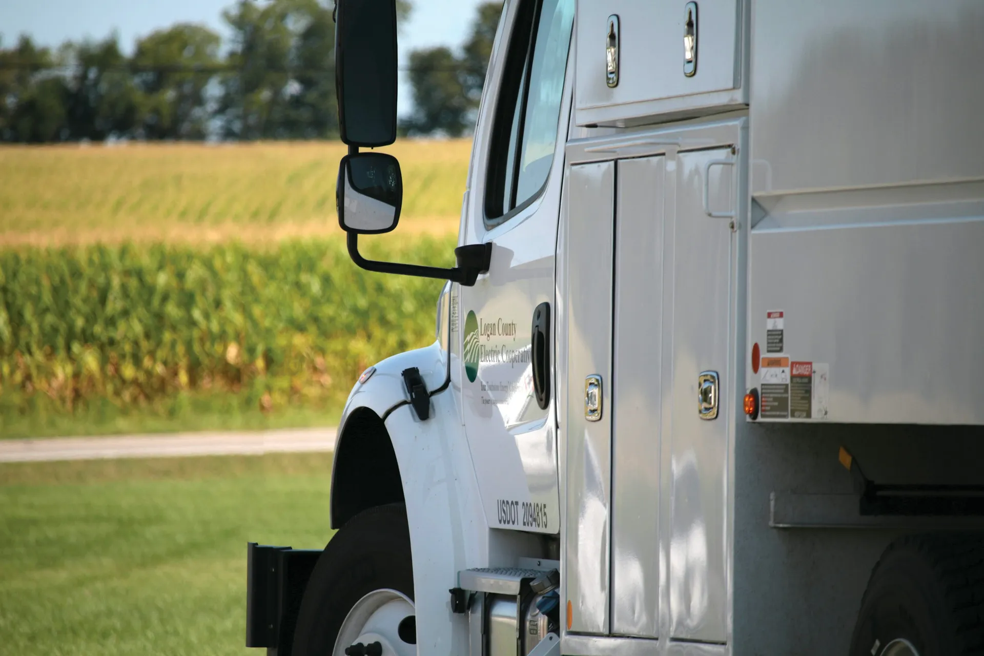 White service truck staged beside a roadway and field