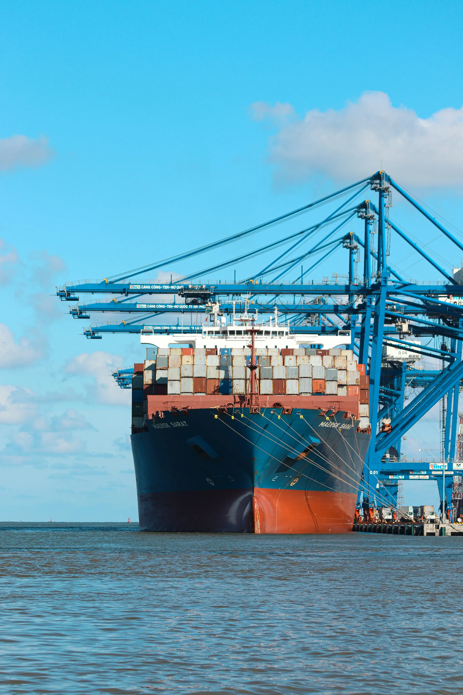Container ship and gantry cranes working together at a busy cargo port